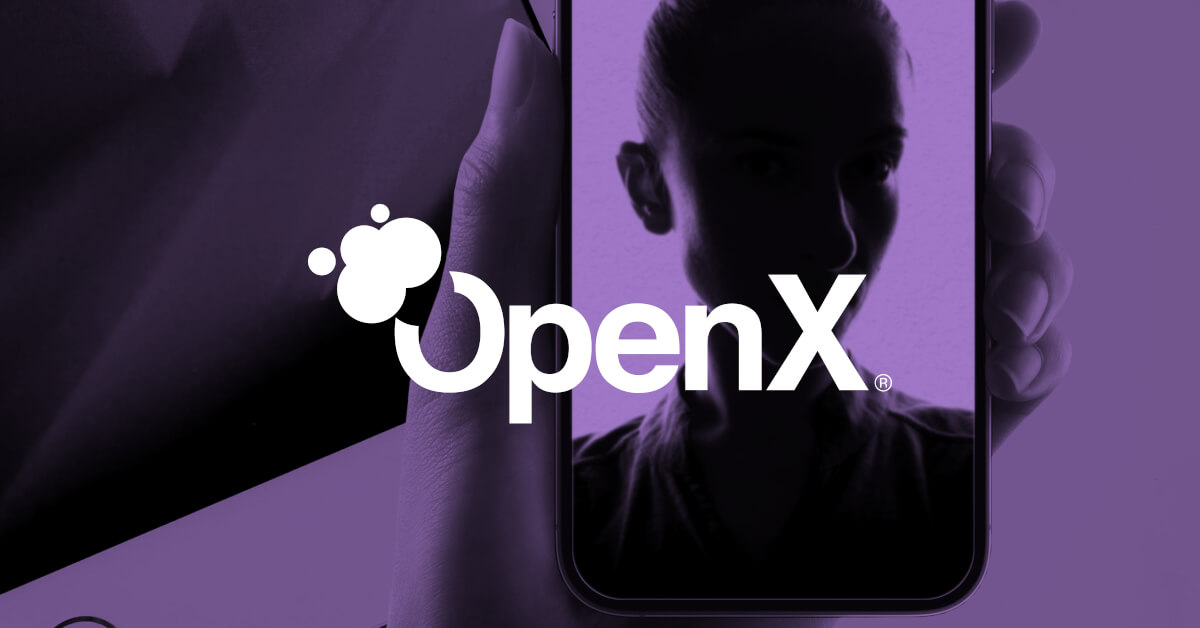 A woman is holding up a phone with the OpenX logo on it.