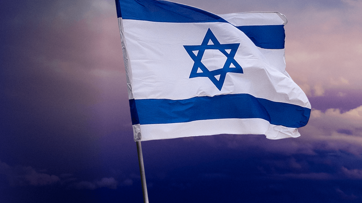 An Israeli flag waving in the wind at an event.